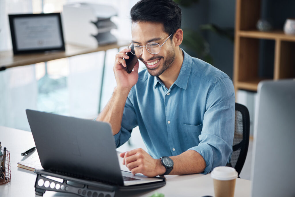 An office worker smiles and listens to a client on the phone. 